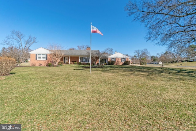 view of front of house featuring a front yard, brick siding, and a chimney