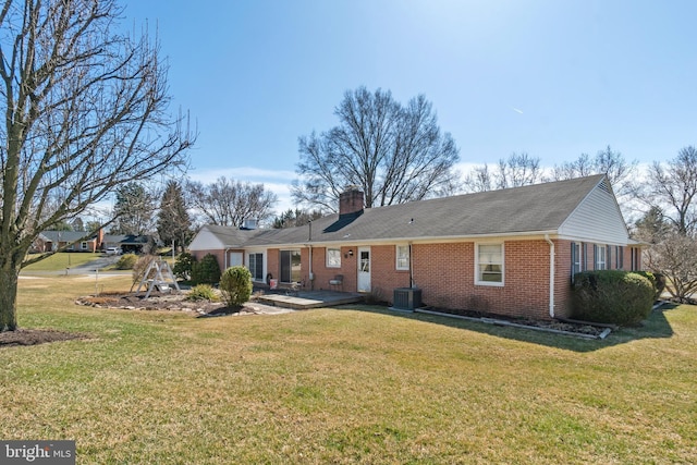 rear view of property with a lawn, brick siding, and a chimney