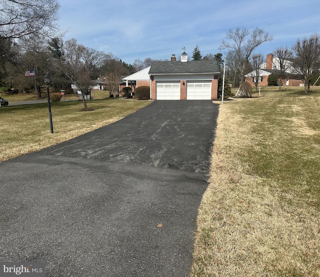 exterior space with aphalt driveway, brick siding, a chimney, and a front yard