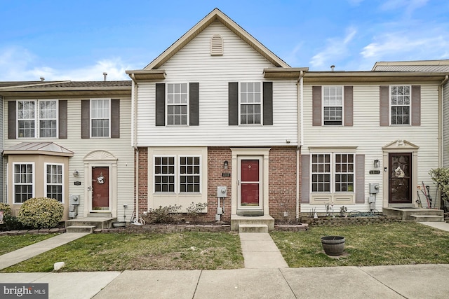 townhome / multi-family property with a front yard and brick siding