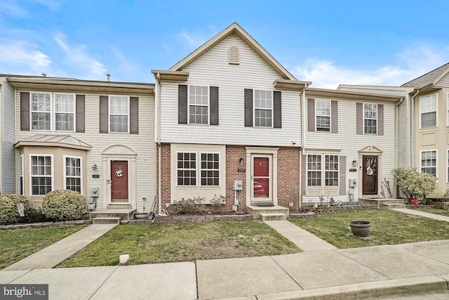 townhome / multi-family property featuring a front yard and brick siding