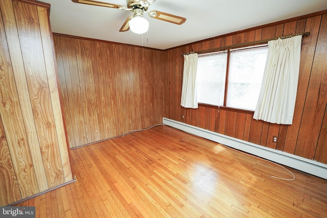 unfurnished room featuring wooden walls, wood-type flooring, baseboard heating, and ceiling fan