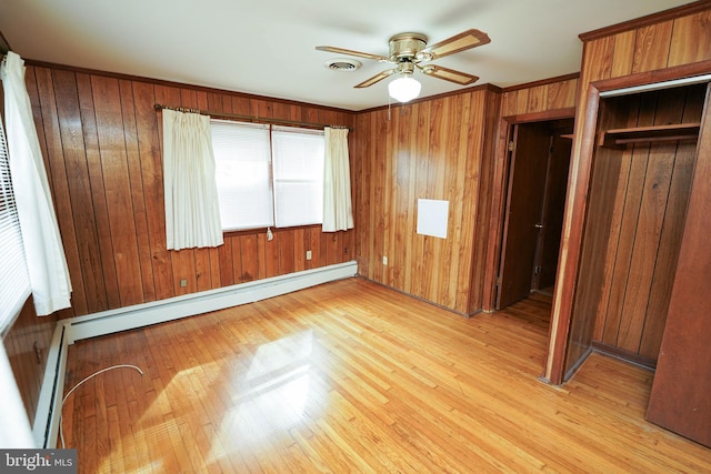 unfurnished bedroom with light wood finished floors, visible vents, a baseboard heating unit, a closet, and a baseboard radiator