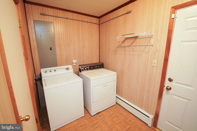 laundry area featuring a baseboard radiator, laundry area, electric panel, wood walls, and washer and clothes dryer