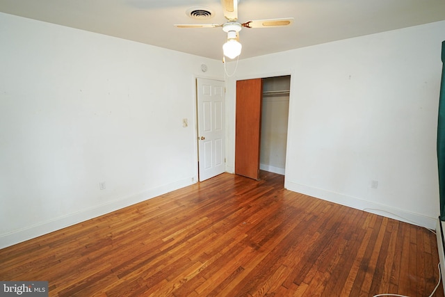 unfurnished bedroom with wood finished floors, visible vents, a closet, and baseboards