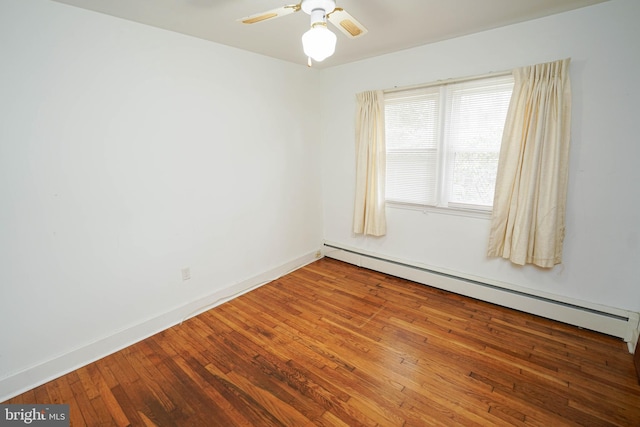 spare room featuring baseboard heating, ceiling fan, baseboards, and hardwood / wood-style floors