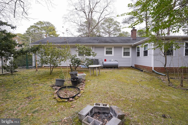 rear view of property with heating fuel, fence, a yard, a garden, and a chimney