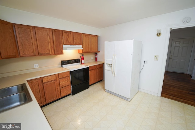 kitchen with a sink, light countertops, electric stove, white refrigerator with ice dispenser, and under cabinet range hood