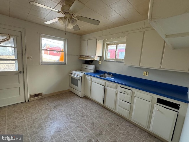 kitchen with visible vents, under cabinet range hood, gas range gas stove, baseboards, and ceiling fan