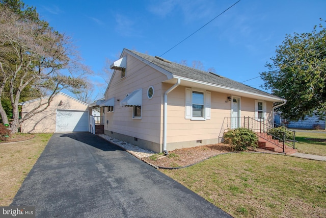 view of front of home featuring a detached garage, aphalt driveway, a front yard, an outdoor structure, and crawl space