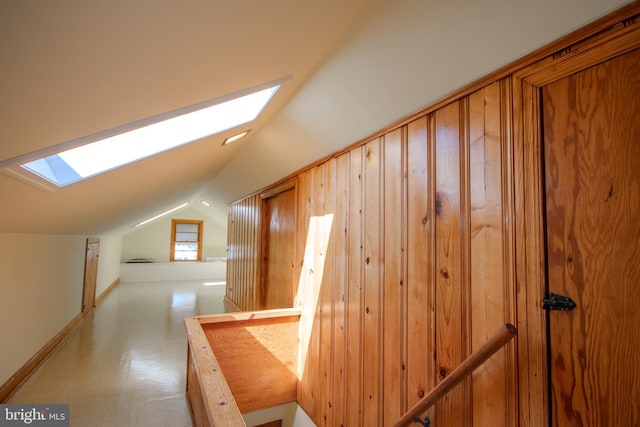 interior space featuring vaulted ceiling with skylight and baseboards