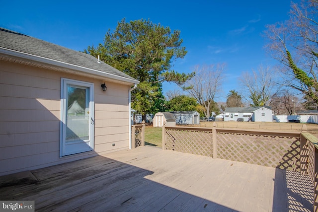 wooden deck with a storage shed, an outbuilding, and fence