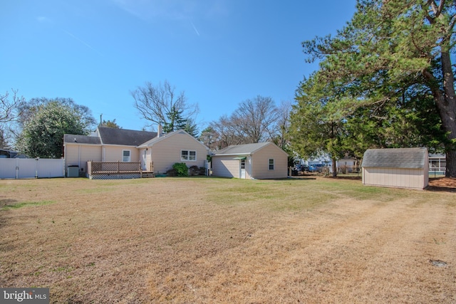 exterior space featuring a storage shed, a lawn, fence, and an outdoor structure