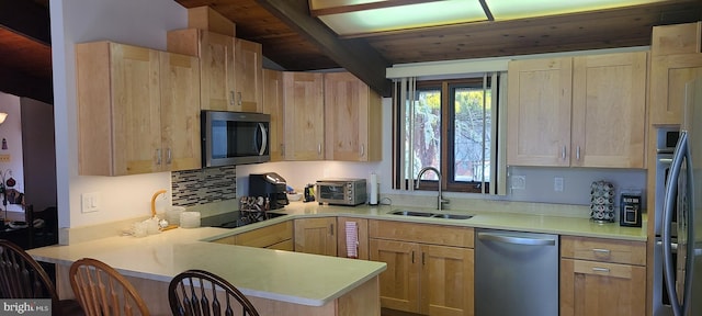 kitchen featuring light brown cabinets, a sink, stainless steel appliances, a peninsula, and light countertops