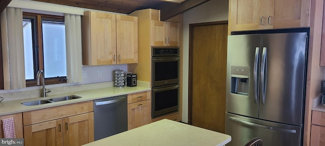 kitchen featuring light brown cabinetry, stainless steel appliances, light countertops, and a sink