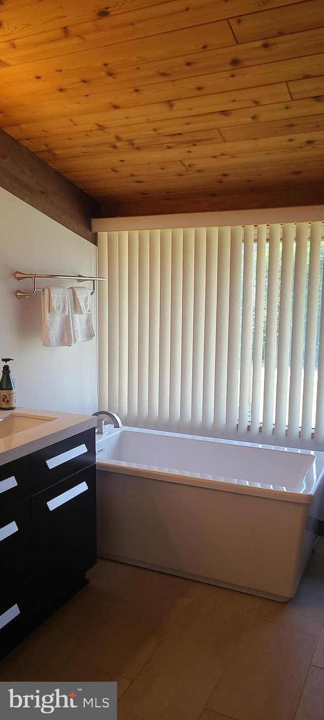 bathroom with a tub, vanity, wooden ceiling, and tile patterned floors