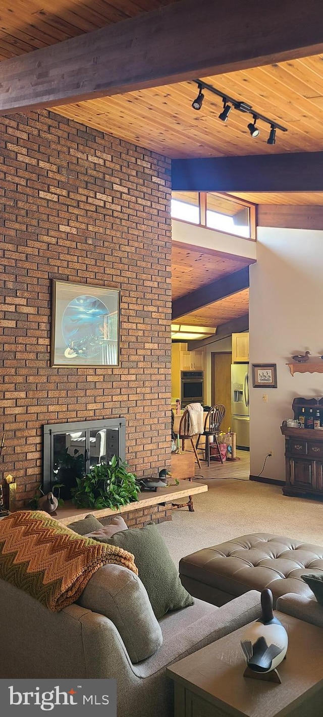 sunken living room with beamed ceiling, wooden ceiling, rail lighting, carpet flooring, and a towering ceiling