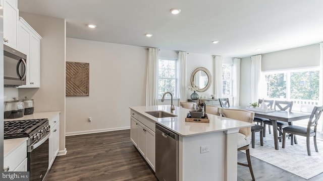 kitchen featuring a center island with sink, recessed lighting, appliances with stainless steel finishes, dark wood-style floors, and a sink