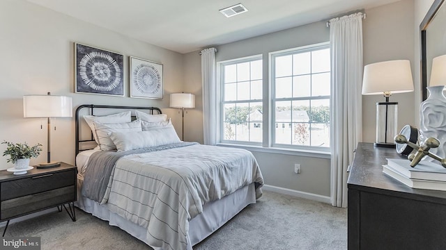 bedroom featuring visible vents, light colored carpet, and baseboards