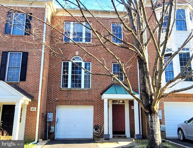 townhome / multi-family property featuring an attached garage, brick siding, and driveway