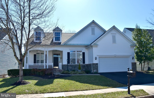 view of front facade featuring driveway, a standing seam roof, a porch, a front lawn, and board and batten siding