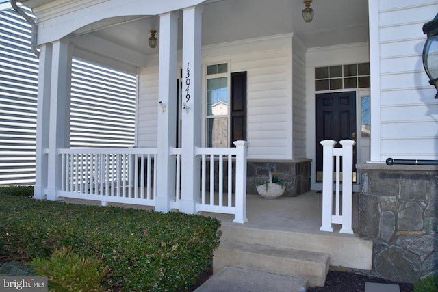 doorway to property with stone siding and covered porch