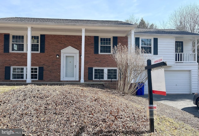 split foyer home featuring aphalt driveway, brick siding, and an attached garage