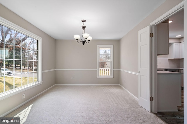 unfurnished dining area featuring baseboards, a chandelier, and carpet flooring