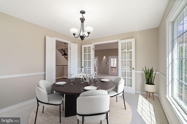 dining area featuring carpet, french doors, baseboards, and a chandelier