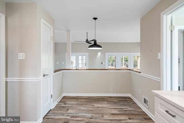 unfurnished dining area with visible vents, plenty of natural light, baseboards, and wood finished floors