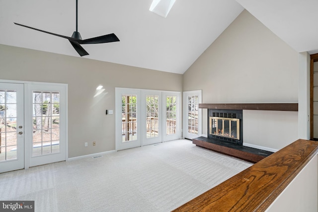 carpeted living area featuring baseboards, french doors, a glass covered fireplace, high vaulted ceiling, and a ceiling fan