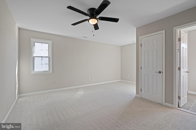 unfurnished bedroom featuring visible vents, baseboards, light colored carpet, and a ceiling fan