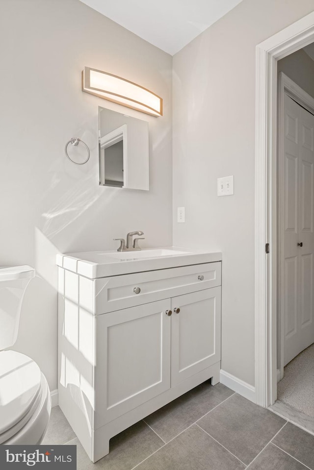 bathroom featuring vanity, toilet, baseboards, and tile patterned flooring