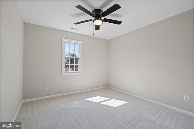 carpeted spare room featuring visible vents, a ceiling fan, and baseboards