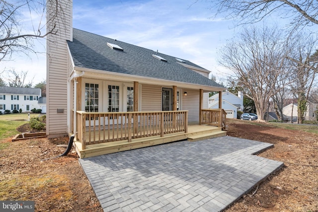 view of front of home featuring a patio, roof with shingles, and a chimney