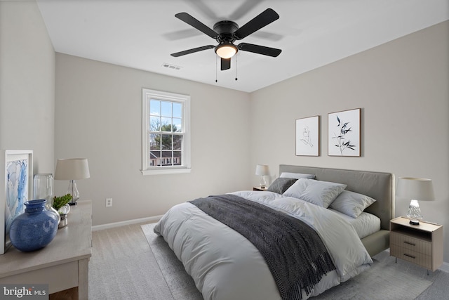 bedroom with visible vents, light colored carpet, baseboards, and ceiling fan