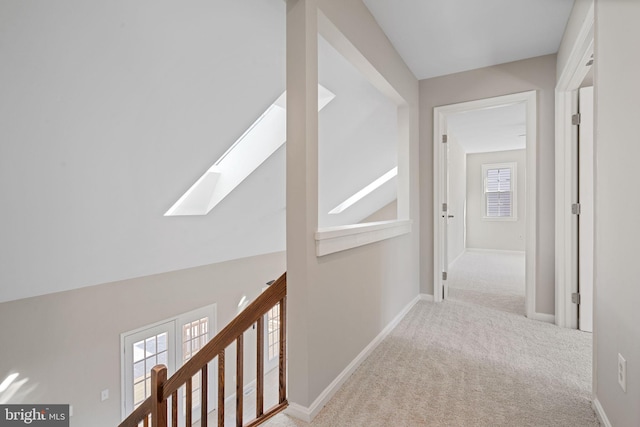 hallway with baseboards, a skylight, and carpet flooring