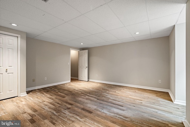 interior space featuring recessed lighting, a paneled ceiling, baseboards, and wood finished floors