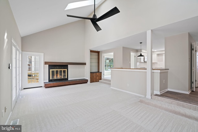 unfurnished living room featuring a glass covered fireplace, baseboards, and carpet floors