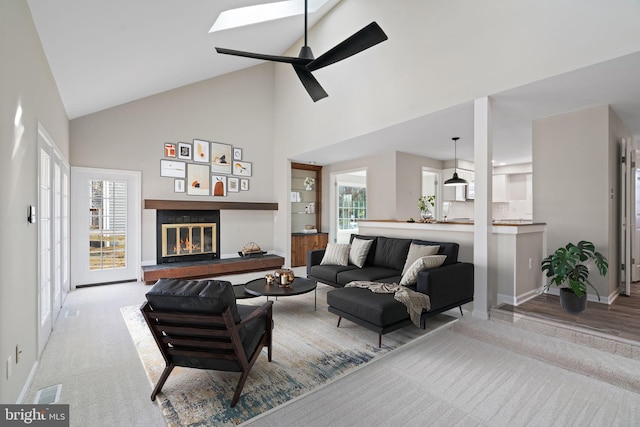 living room featuring a glass covered fireplace, plenty of natural light, ceiling fan, and high vaulted ceiling