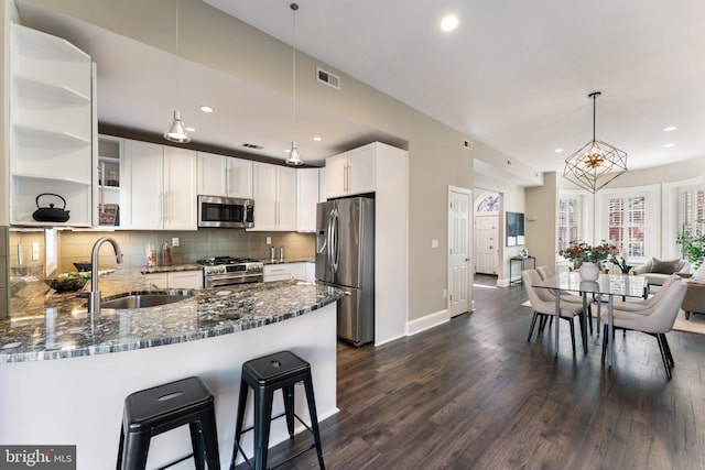 kitchen with visible vents, a sink, tasteful backsplash, stainless steel appliances, and dark stone counters