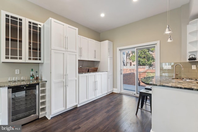 kitchen with wine cooler, dark stone counters, dark wood-type flooring, and a sink