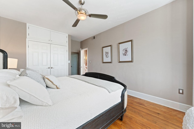 bedroom with light wood-type flooring, a closet, baseboards, and ceiling fan