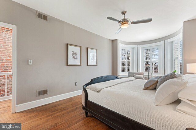 bedroom featuring hardwood / wood-style floors, baseboards, visible vents, and ceiling fan