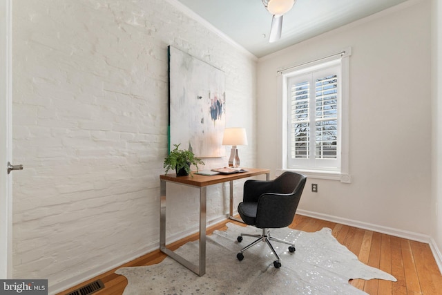 home office featuring hardwood / wood-style flooring, crown molding, baseboards, and visible vents