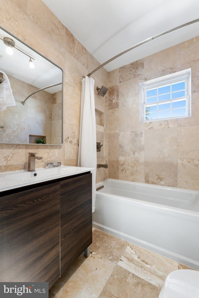 bathroom featuring tile walls, toilet, shower / bath combo with shower curtain, and vanity