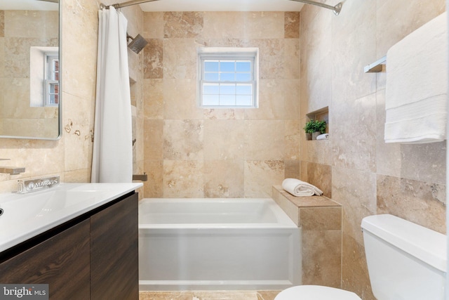 full bath with vanity, toilet, tile walls, and shower / bath combo