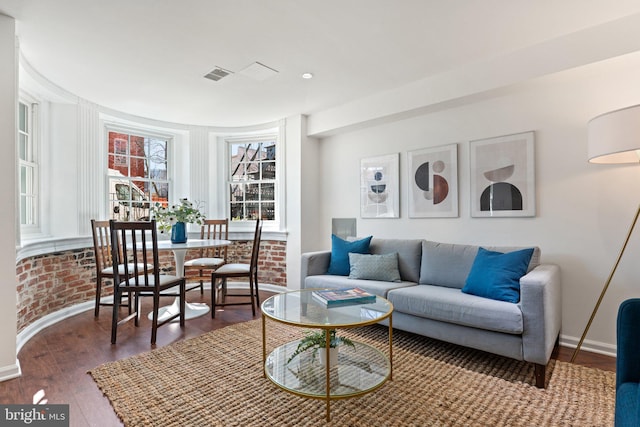 living room featuring visible vents, baseboards, and wood finished floors