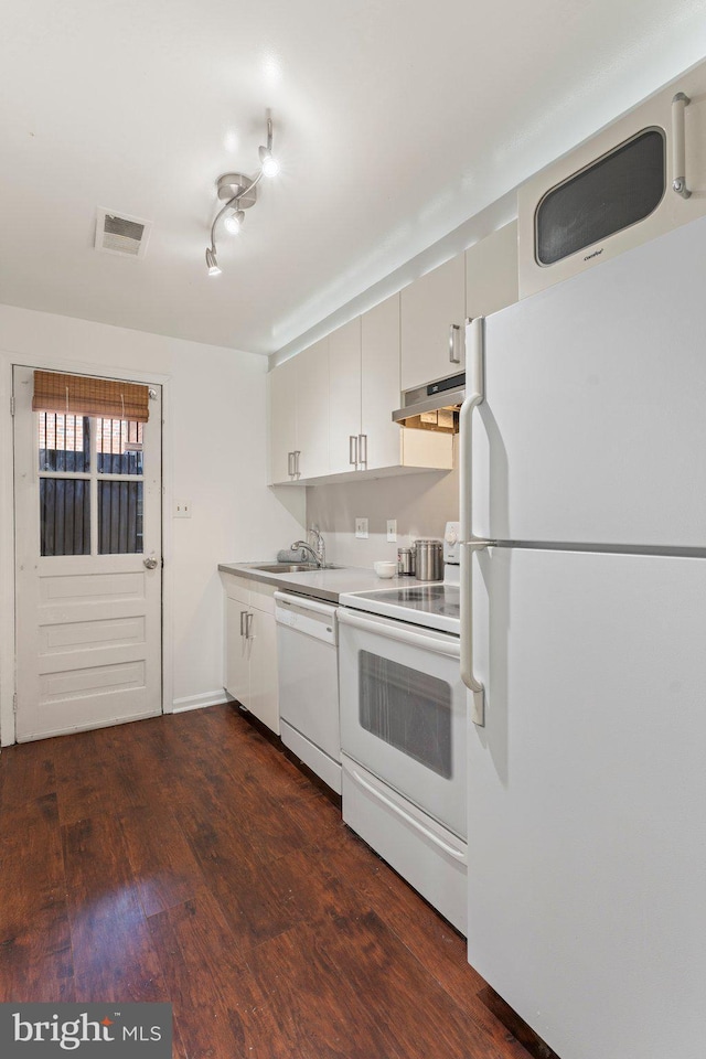 kitchen with visible vents, under cabinet range hood, a sink, dark wood finished floors, and white appliances