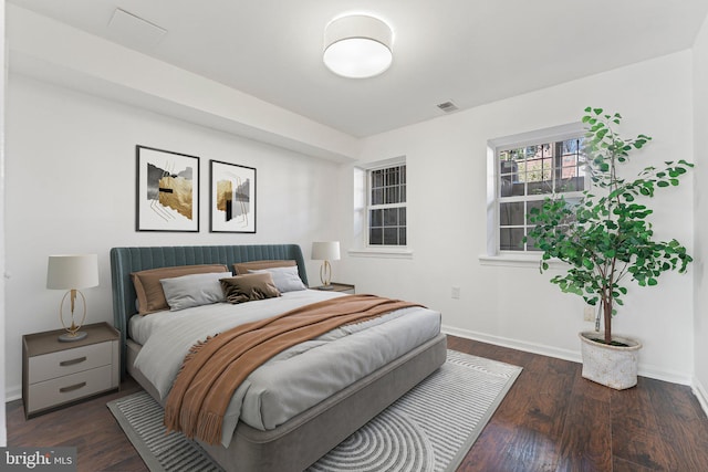 bedroom with visible vents, baseboards, and wood finished floors